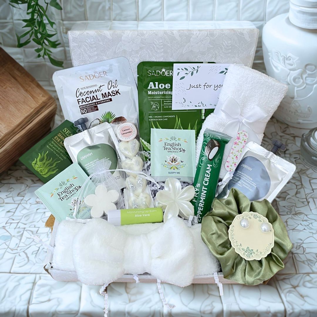 Sister Birthday self care present. A curated spa gift basket filled with skincare and self-care items, including SADoO facial masks, a green silk scrunchie, pearl earrings, a white hairand, a white face towel, Pearly Hair Clip, Frys Chcolate, Sleepy tea, seaweed eye soothers, lemon lavender wax melts, shampo and body was pouch, Mini nail file, arranged in a white box with pretty tissue and gift card of your choice
