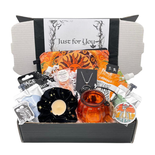 Gothic Gift box containing a good selection of items, glass pumpkin lantern, velvet star scrunchie, triple moon necklace, skull earrings, wax melts, scented tealight, shampoo, body wash, make up bag, Glitter gel mask, orange gel peel off mask, stickers, paked in to a black gift box.