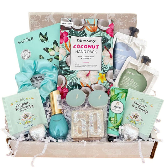 A curated self-care gift box filled with multiple beauty products including Dermvav10 Coconut Hand Pack, Sadoer  sheet mask, English Tea Shops tea bags, a teal nail polish, glittery wax melts, wrapped chocolates, satin scrunchie, Handcream scented candles in a box with fancy tissue and gift card of your choice.